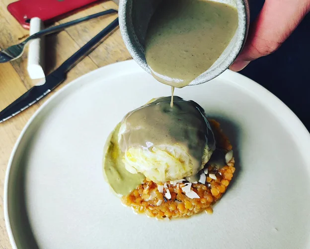 Photo d'une assiette du restaurant Yuta où un coulis est versé sur les aliments dans l'assiette