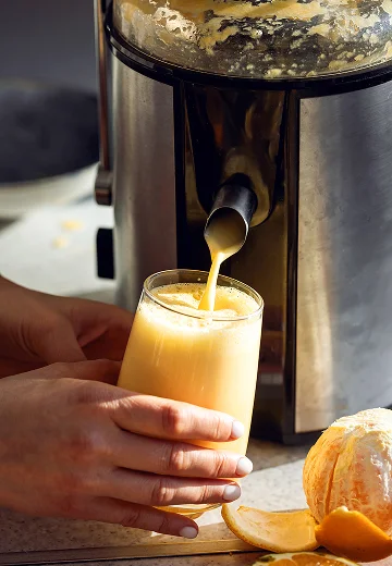 photo d'une personne en train de se servir un jus vitaminé à une centrifugeuse