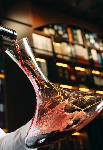 photo d'un personne en train de verser du vin rouge dans une carafe