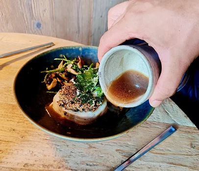 Photo d'une assiette contenant de la viande sur laquelle on verse de la sauce