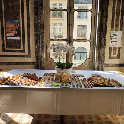table de buffet dressée avec bouchées salées, bouteilles de vin et deux services présents pour le service